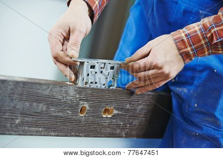 Close-up carpenter hands with doorlock during lock process installation into wood door