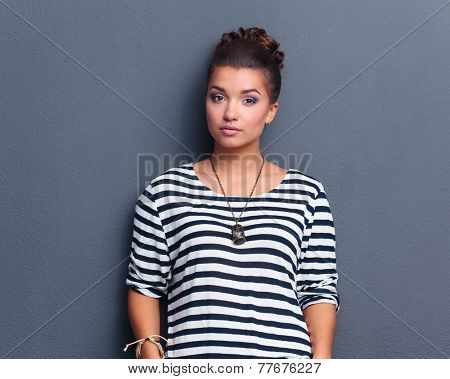 A young woman standing, isolated on graybackground