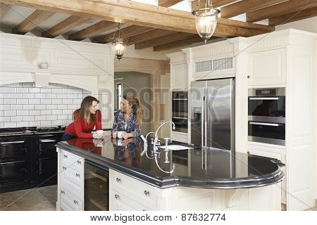 Mature Female Friends Standing In New Luxury Fitted Kitchen And