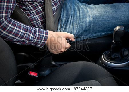 Young Man Pulling Handbrake Lever In Car