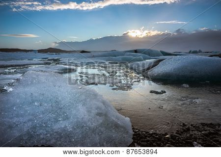 Glacier ice lagoon during sunset in Jokullsarlon, Iceland. The glacier breaks up into ice blocks in the lagoon before flowing out to sea as icebergs.