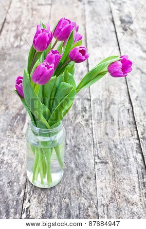 Bouquet Of Violet Tulips On The Oak Brawn Table In A Clear Glass Jar