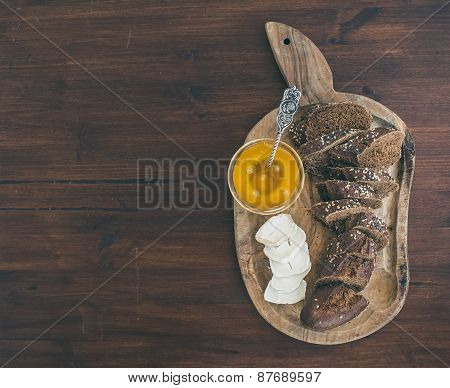 Fresh Dark Baguette Cut In Slices, Goat Brie Cheese And Honey On A Rustic Wooden Board
