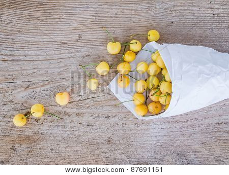 Yellow Sweet-cherries In A Paperbag On A Rought Wood Surface