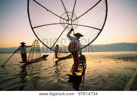 Three fishermen catches fish for food in sunrise in Inle Lake, Myanmar