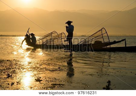 Three fishermen catches fish for food in sunrise in Inle Lake, Myanmar