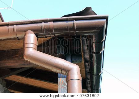 brown rain gutter on a home against blue sky