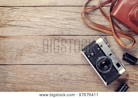 Vintage film camera with case on wooden table. Top view with copy space. Toned