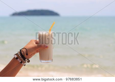 Female Hand Holding Milk Shake With Tropical Sea View Background