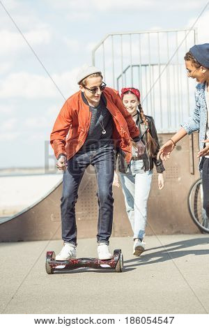 stylish teenage boy riding gyroboard with friends near by hipster style concept