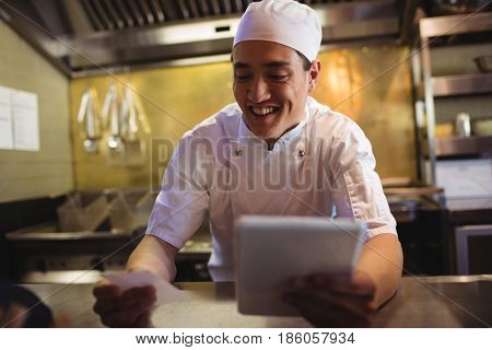 Smiling chef looking at an order list in the commercial kitchen