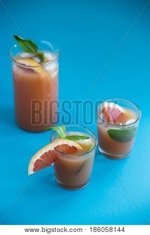 Grapefruit alcoholic cocktail with pieces of fruit, ice and mint