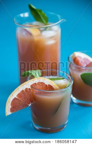 Grapefruit alcoholic cocktail with pieces of fruit, ice and mint