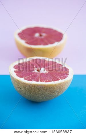 Cut in half a grapefruit on a pink and blue background