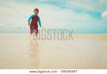 little boy enjoy play with water on tropical beach