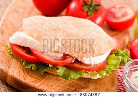 Puccia bread with mozzarella and tomato on cuttingboard.