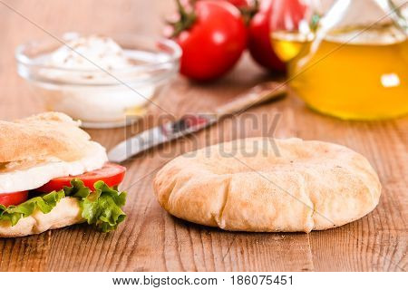 Puccia bread with mozzarella and tomato on wooden table.