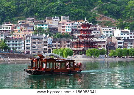 Zhenyuan, China - May 2, 2014: Tourists floating on the boat on Wuyang River in ancient town Zhenyuan of Guizhou Province.
