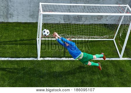 Soccer football goalkeeper making diving save on green fuild