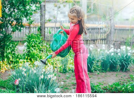 beautiful little girl watering flowers in the garden