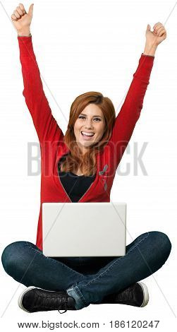 Red headed woman sitting crosslegged and celebrating with an open laptop in front of her