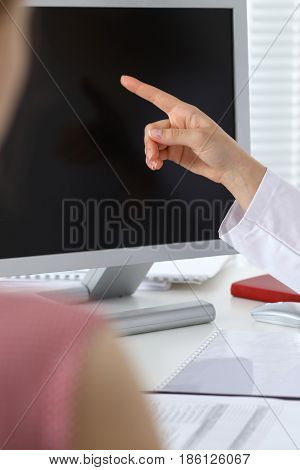 Close-up of a doctor and patient sitting at the desk while physician pointing into monitor computer. Medicine and health care concept.
