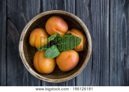 Ripe orange apricots in a clay bowl on a wooden table