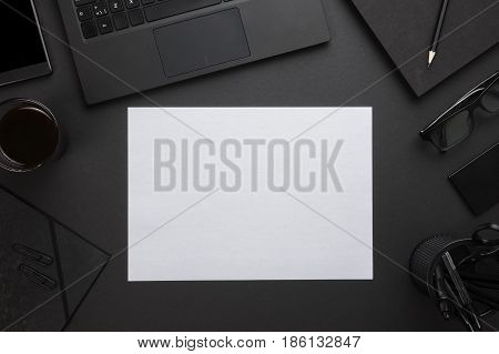 Directly above shot of blank white paper with laptop and office supplies on gray desk