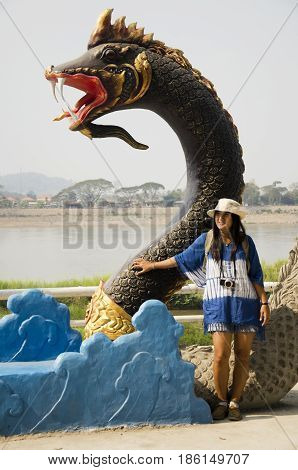 Travelers thai woman visit and posing for take photo with black naga statue at mae khong riverside in Chiang Khan for writing blog on February 21 2017 in Loei Thailand
