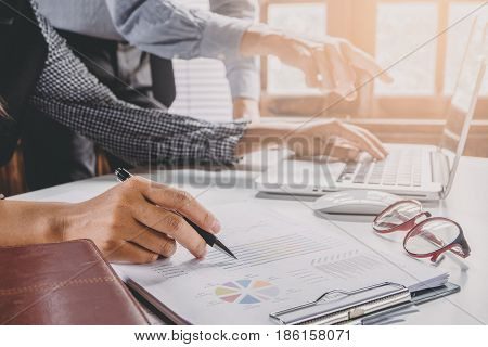 Image of two young business team using laptop computer and graph financia at meeting.Close up business team analysis and strategy concept.