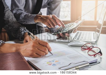 Image of two young business team using calculator and graph financia at meeting.Close up business team analysis and strategy concept.