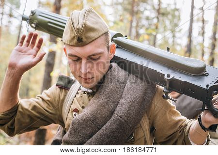 Dyatlovichi, Belarus - October 1, 2016: Young Reenactor Man Dressed As Russian Soviet Red Army Infantry Soldier Of World War II Marching In Forest With Weapon Machine-gun At Historical Reenactment