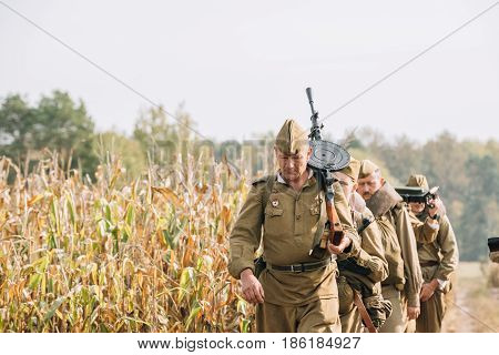 Dyatlovichi, Belarus - October 1, 2016: Reenactors Men Dressed As Russian Soviet Red Army Infantry Soldiers Of World War II Marching In Field With Weapon Machine-gun At Historical Reenactment