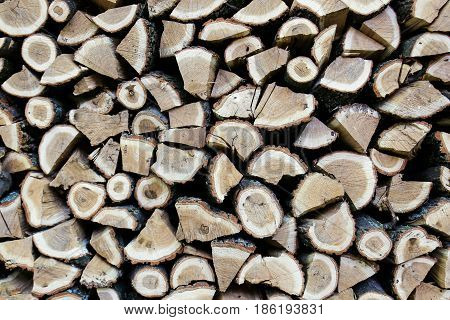 Background of dry chopped oak firewood logs stacked up on top of each other in a pile
