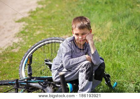 An upset boy sitting on a broken bike.
