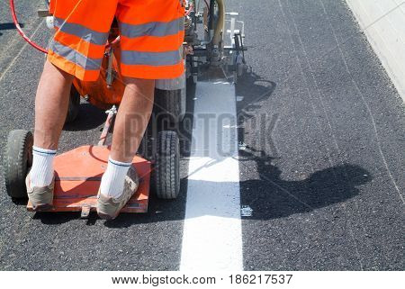 Bissone Switzerland - 20 June 2011: Machine eject and worker on road and traffic sign painting