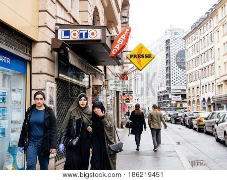 STRASBOURG FRANCE - MAY 7 2017: Three muslims girls walking on trottoir under Loto and press signage in French city of Strasbourg