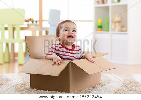 pretty baby infant boy sitting inside a box in new apartment