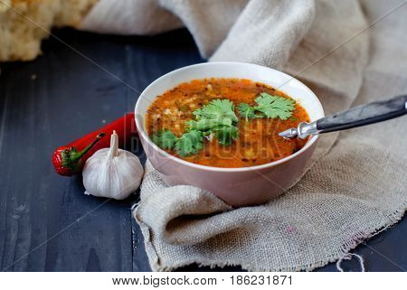 Georgian soup kharcho with cilantro and vegetables. The national Georgian dish is served with fresh lavash. Soup kharcho with vegetables and cilantro on a wooden table.