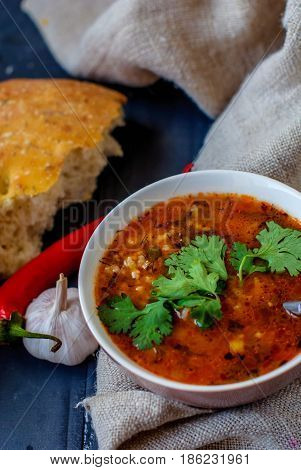 Georgian soup kharcho with cilantro and vegetables. The national Georgian dish is served with fresh lavash. Soup kharcho with vegetables and cilantro on a wooden table.