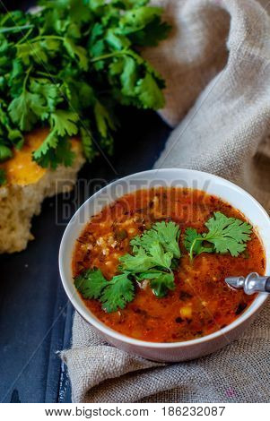 Georgian soup kharcho with cilantro and vegetables. The national Georgian dish is served with fresh lavash. Soup kharcho with vegetables and cilantro on a wooden table.