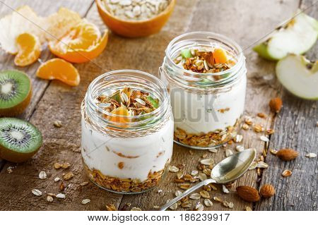 Healthy homemade granola with yogurt and fruits in a rustic jar. Traditional American food on a table. Classic snack. Top view.