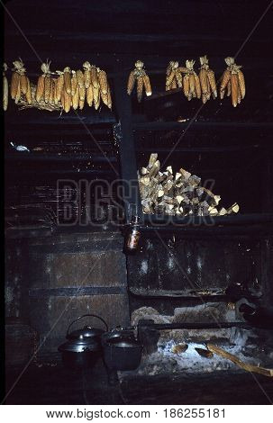 A primitive Ifugao kitchen, with a hearth for cooking with wood, and cobs of corn dangling from the ceiling, in a village near the city of Banaue, Ifugao Province, in the Philippines.