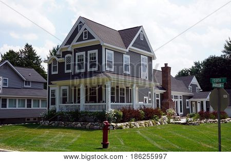 HARBOR SPRINGS, MICHIGAN / UNITED STATES - AUGUST 4, 2016: A large, elegant home, with a wraparound porch, at the corner of Fourth and Harrison Streets in Harbor Springs.