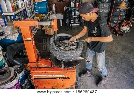 Labuan,Malaysia-May 9,2017:Car tire service mechanic changing car wheel before makes computer wheel balancing on special equipment machine tool in auto repair service in Labuan,Malaysia.