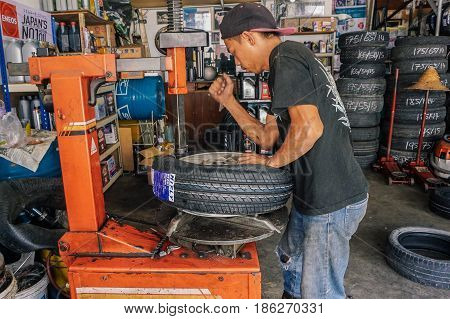 Labuan,Malaysia-May 9,2017:Car tire service mechanic changing car wheel before makes computer wheel balancing on special equipment machine tool in auto repair service in Labuan,Malaysia.