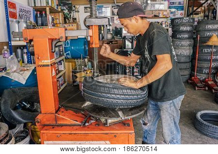 Labuan,Malaysia-May 9,2017:Car tire service mechanic changing car wheel before makes computer wheel balancing on special equipment machine tool in auto repair service in Labuan,Malaysia.