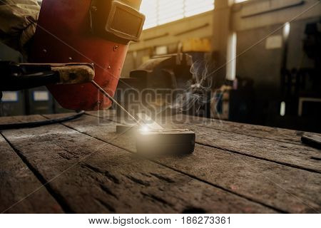 Inverted welding machine welding equipment on a wooden desk with workshop background welding mask leather gloves electrodes high-voltage wires with clips set of accessories for arc welding