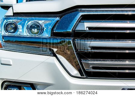 Fragment of the front of the car with a headlight and radiator grille with traces of dirt