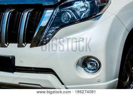 Fragment of the front of the car with a headlight and radiator grille with traces of dirt